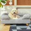 Perro sentado en Topology cama para perros con almohadilla superior y pies de madera