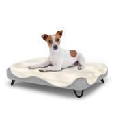 Perro sentado en una pequeña cama para perros Topology con topper de piel de oveja y patas de horquilla de metal negro