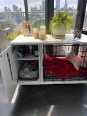 Un cajón blanco para perros Fido con una sección de armario y una cama gris para perros