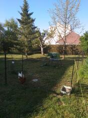 Un gallinero Go detrás de una valla con dos gallinas en un jardín