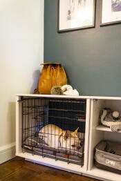 Un perro blanco dormido dentro de un Fido Nook con un armario y un cajón