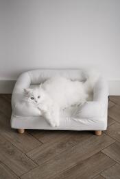 Un gato blanco disfrutando de la comodidad de su cama blanca