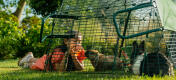 Un niño dando de comer sandía a su conejo a través de la malla del corral.