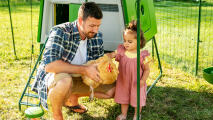 Hombre con su hija sujetando una gallina en un gallinero