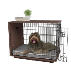 Un perro sentado dentro de un cajón para perros Omlet Fido Studio de nogal.