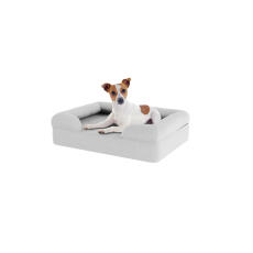 Perro sentado en una pequeña cama de espuma de memoria gris para perros