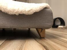 Cama gris con pies cuadrados de madera y topper blanco