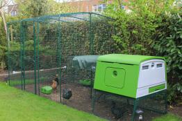 Un gran gallinero verde Eglu Cube con un corral adjunto y gallinas dentro