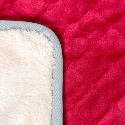 Una foto de cerca de una suave manta roja para la cama del perro.