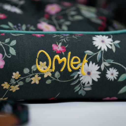 LoGo detalle en una cama nido Omlet en el patrón prado de medianoche