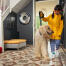 Chica sacando a su perro a pasear con Omlet Topology cama para perros con topper de bolsa de frijoles y pies de barandilla blanca en el fondo