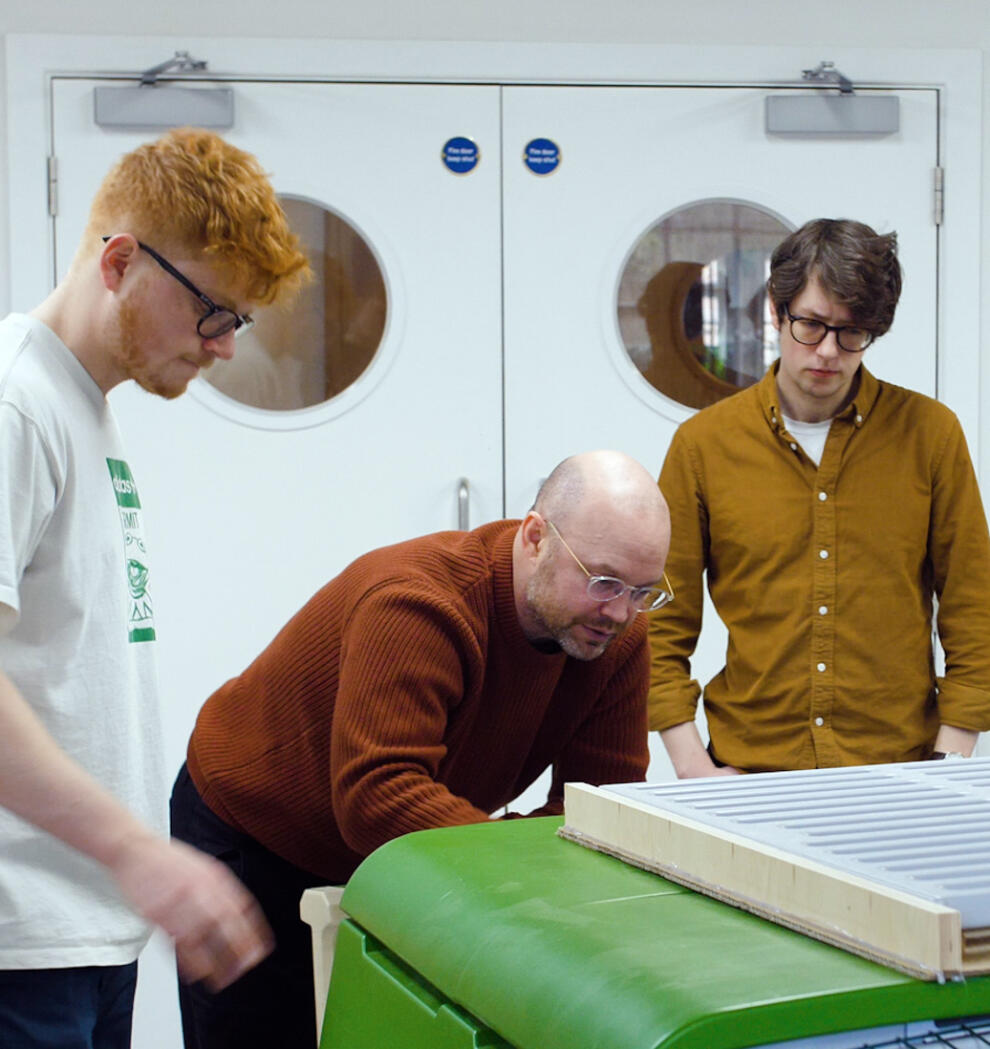 Cuatro hombres examinando el gallinero Eglu Cube en un taller