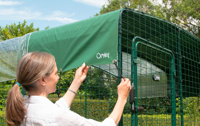 Mujer colocando la cubierta de recinto de omlet a un recinto para gatos